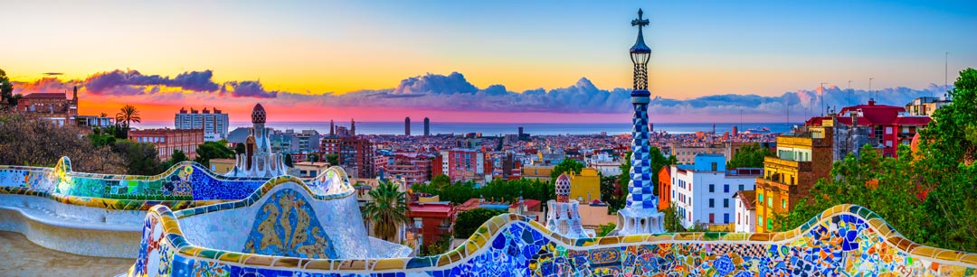 Sunrise in Barcelona from Parc Güell, which was designed by famed architect Antoni Gaudi. The park is known for its vibrant mosaics, architecture, and panoramic city views.